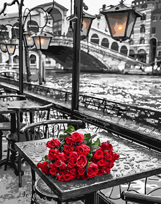 Bouquet of red roses on a table with a canal and bridge in the background