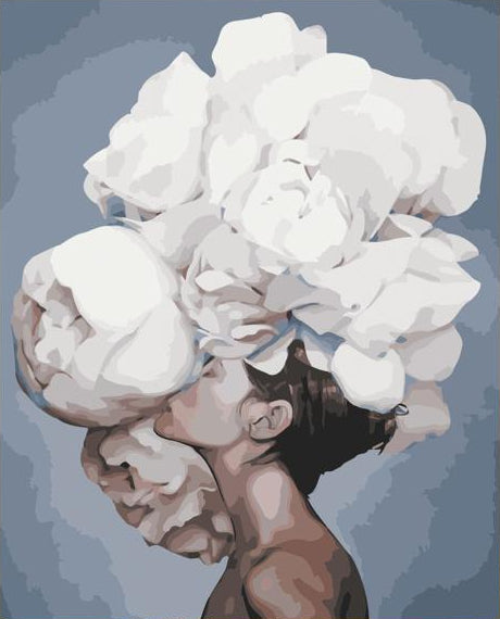 A vertical canvas painting of a woman with large white flowers covering her face, displayed on a white tabletop next to a white alarm clock, with paint pots, brushes, and a paint palette in front. The background wall is light gray.