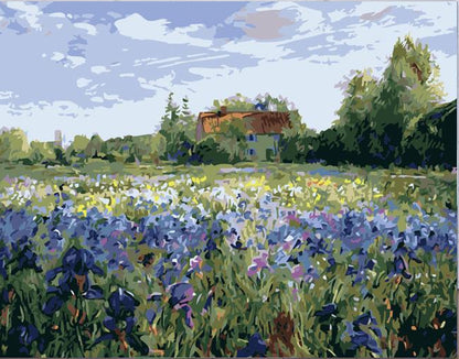A canvas painting of a lavender and blue flower field with a small house and trees under a cloudy sky, displayed on a wooden surface against a white brick wall with paint supplies nearby.